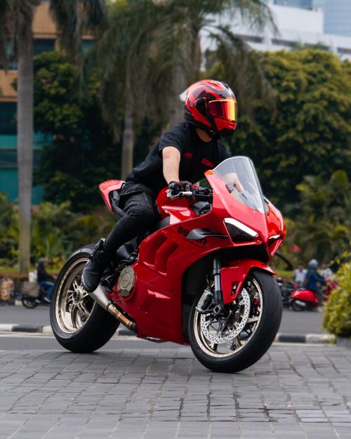 Free Man riding a red sports motorcycle in an urban environment, capturing speed and motion. Stock Photo