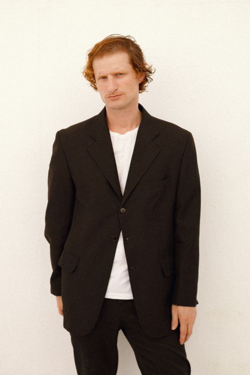 Free A relaxed portrait of a man wearing a black blazer against a plain backdrop. Stock Photo
