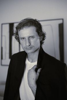 Expressive black and white portrait of a man wearing a suit jacket indoors, creating a vintage mood.