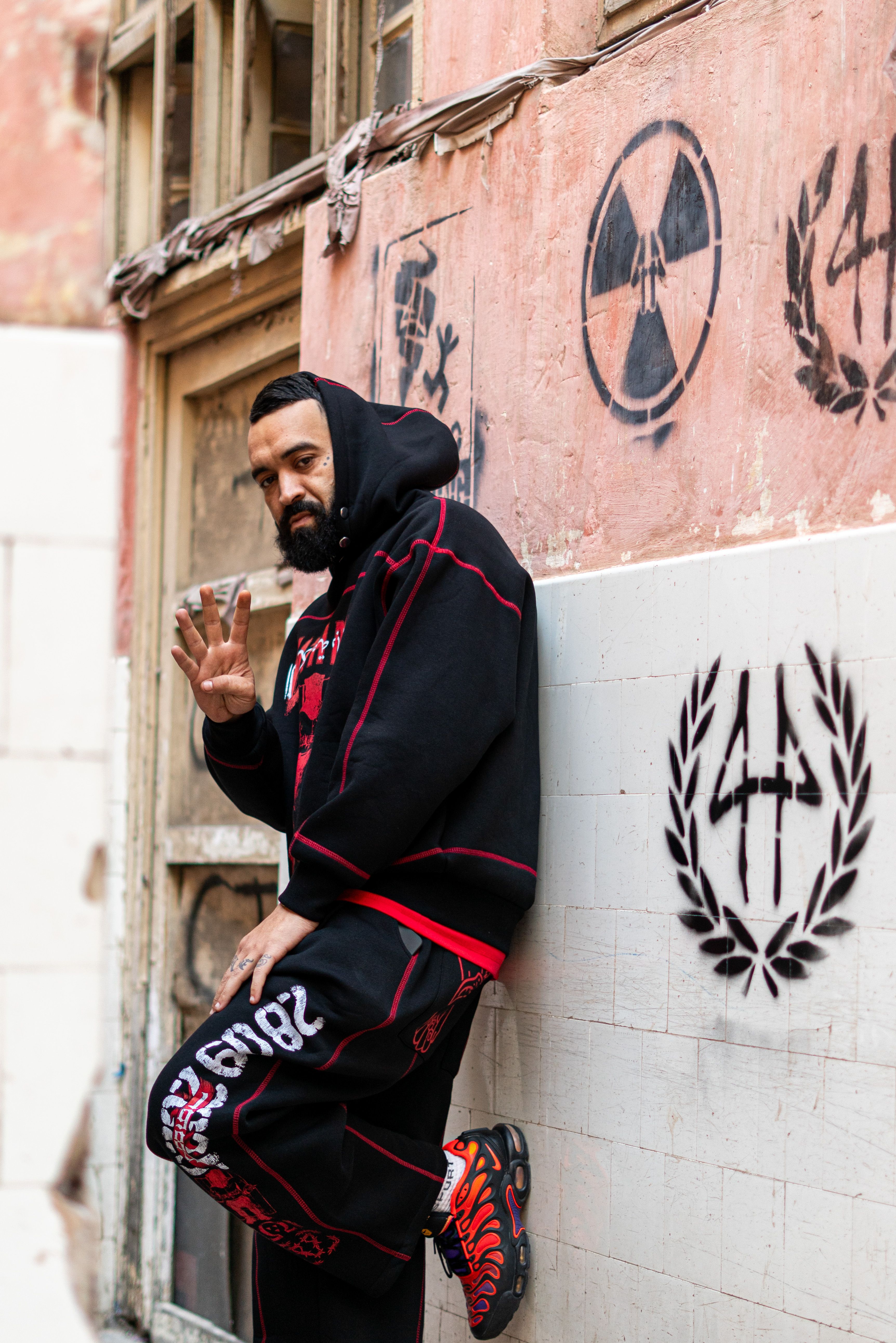Man in stylish streetwear posing in front of graffiti wall in Morocco.