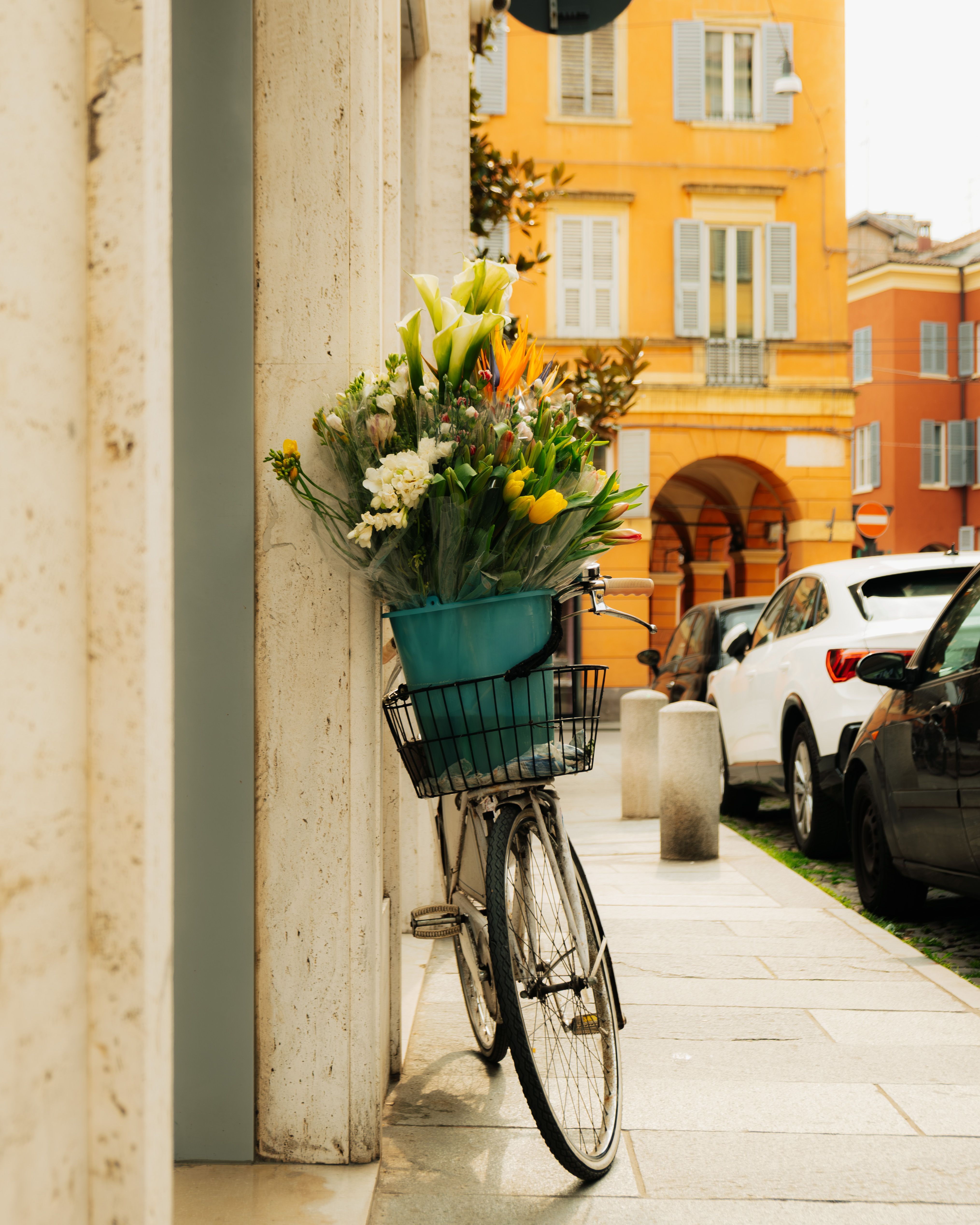 Charming scene of a bicycle with flowers on a street in Modena, Italy.