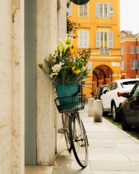 Charming scene of a bicycle with flowers on a street in Modena, Italy.