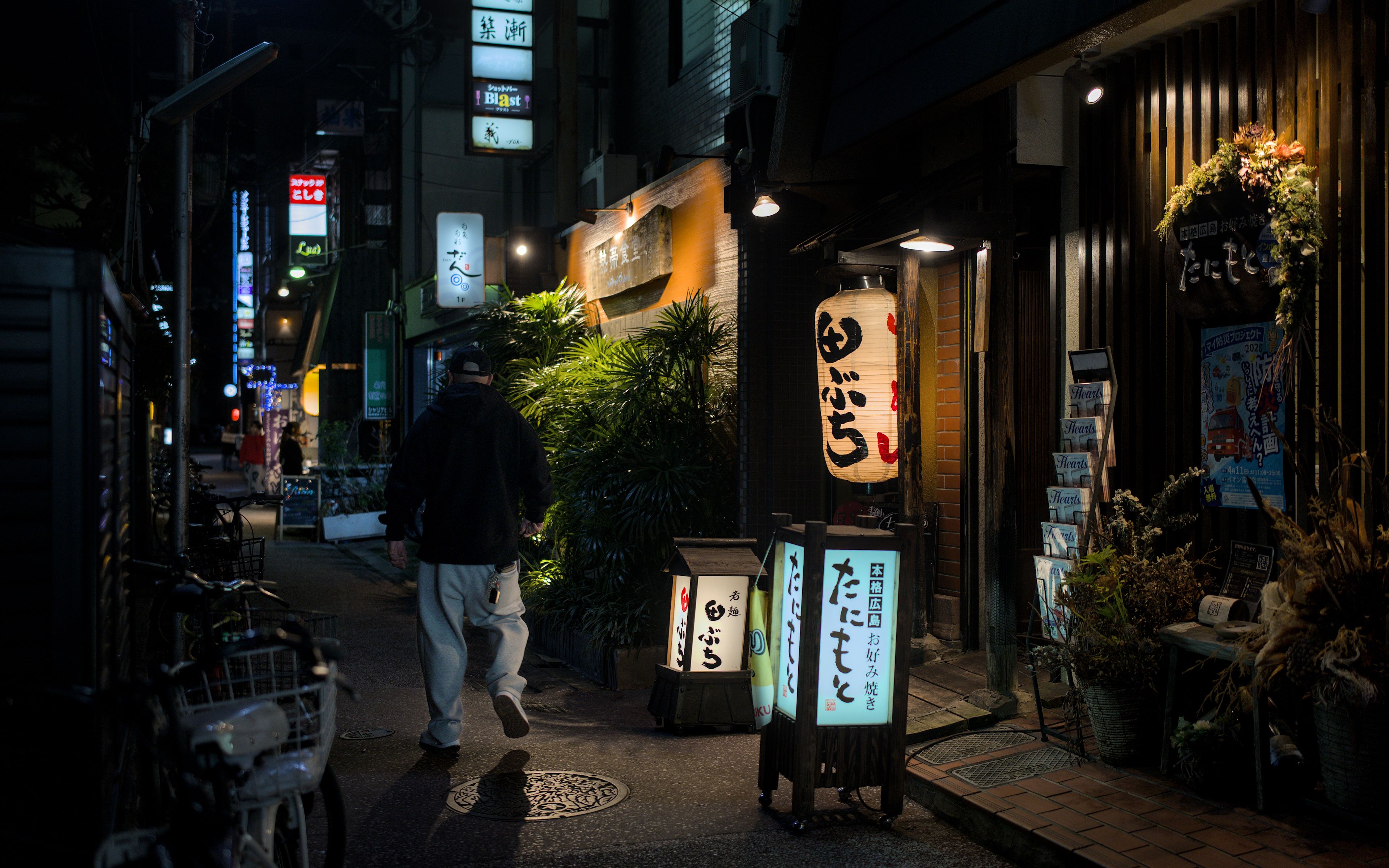 Moody night scene of a vibrant street in Takatsuki, Osaka, showcasing lantern-lit alley and local restaurants.