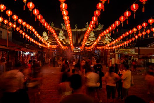 Crowds admire traditional lanterns at a Chinese temple during a lively night festival.