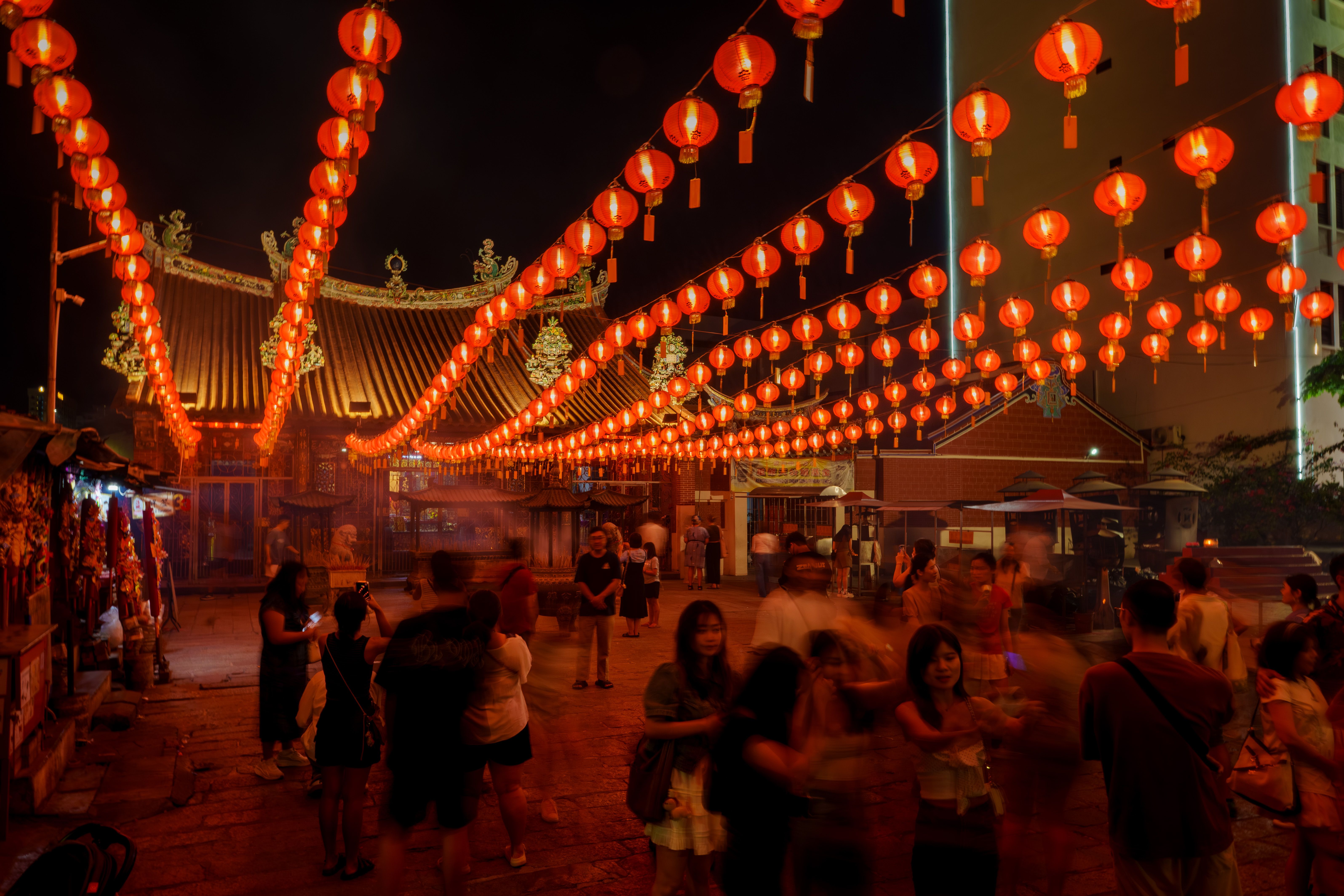 Crowd enjoying a night market under vibrant red lantern decorations in Chinatown.