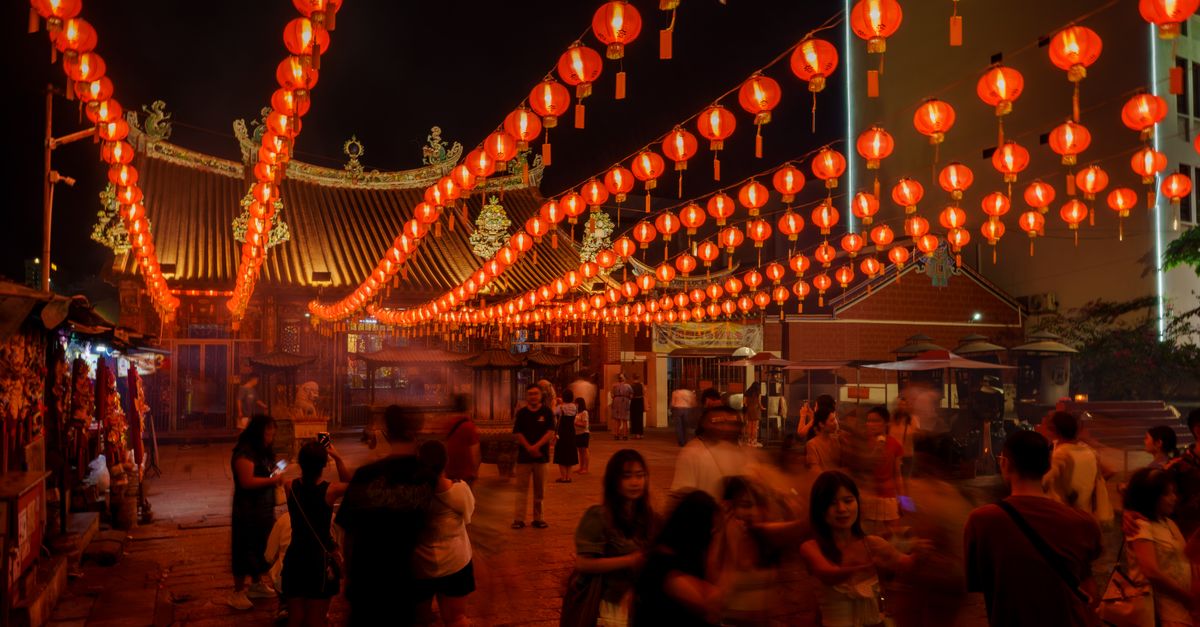 Crowd enjoying a night market under vibrant red lantern decorations in Chinatown.