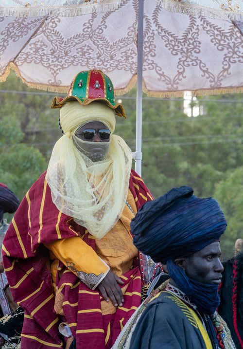 Free Men in traditional African attire participate in an outdoor festival, showcasing vibrant colors and cultural heritage. Stock Photo