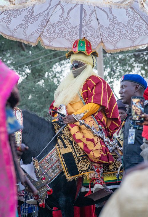 Free Colorful African royal procession featuring traditional attire and horse under a decorated umbrella. Stock Photo