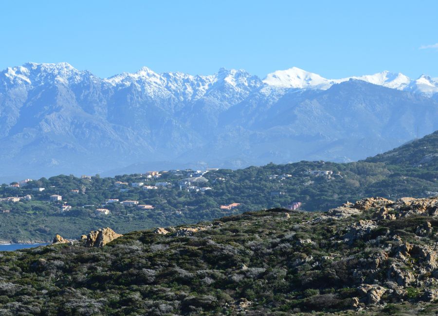 Beautiful snow-capped mountains and rugged hills viewed from Calvi, Corsica, France.