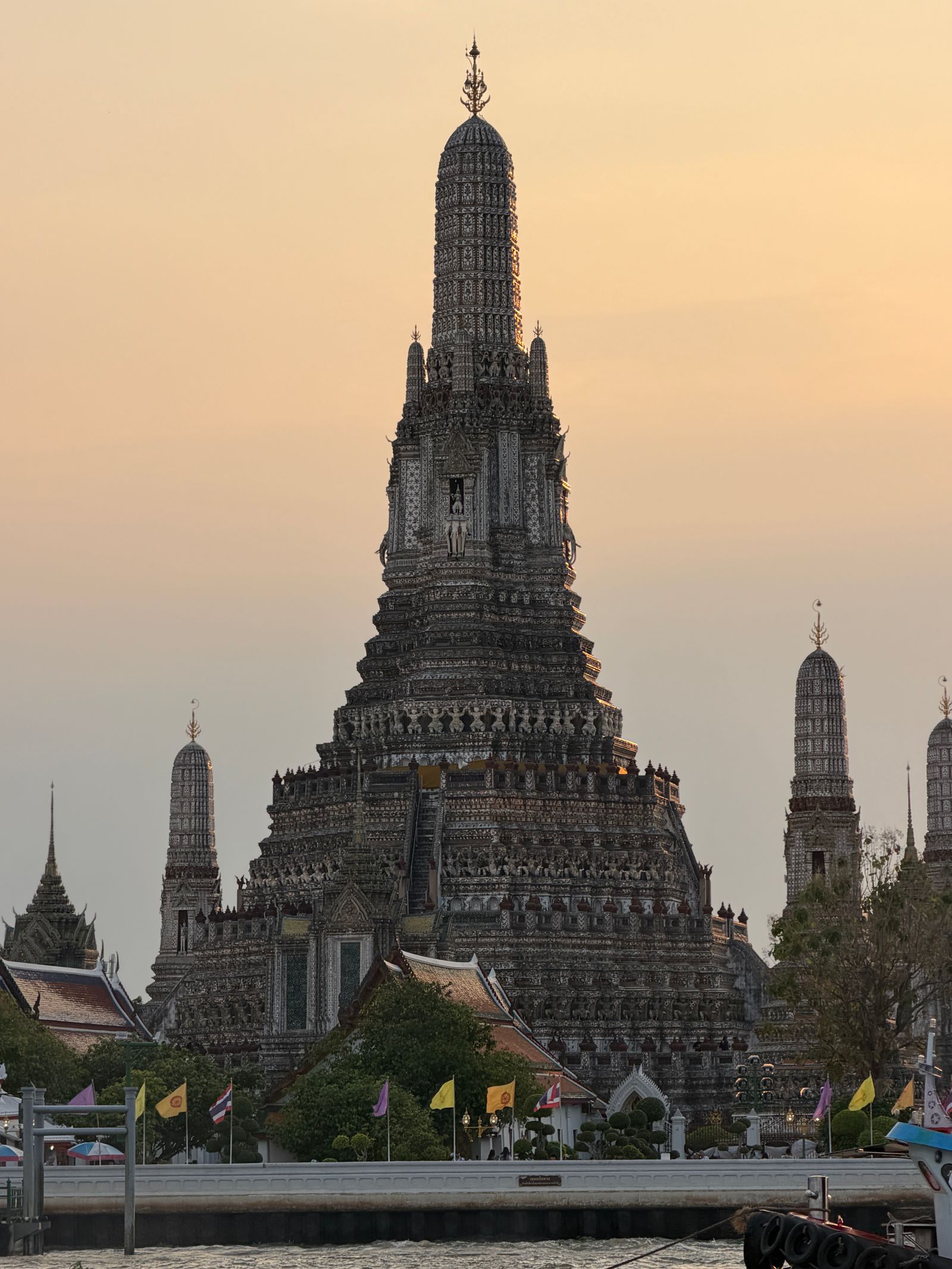 Wat Arun's central spire silhouetted against a golden sunset in Bangkok