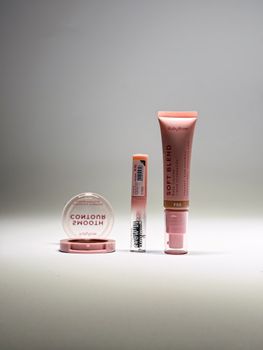 Minimalist display of three pink makeup products showcasing subtle beauty and elegance in soft lighting.