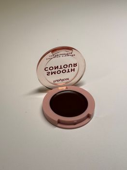 A sleek round makeup compact with an open lid reflecting its branding.