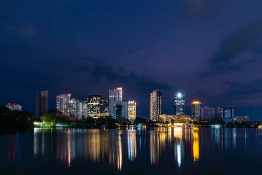 Breathtaking view of Colombo skyline at night with skyscraper reflections on water.