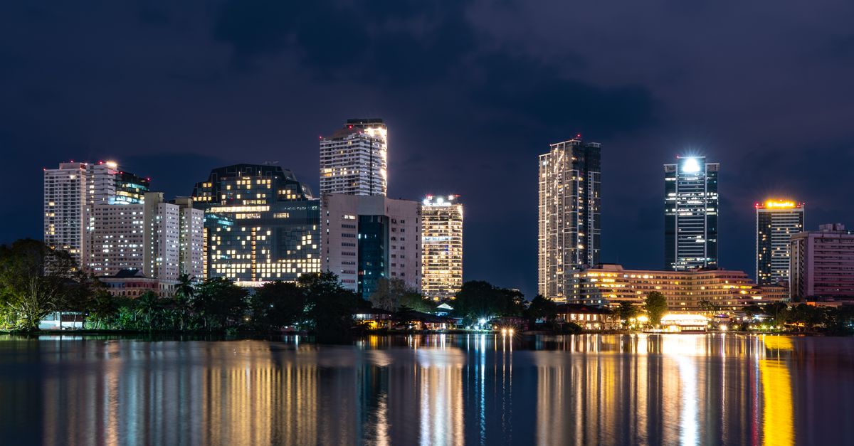 Stunning night view of Colombo skyline with reflections on the water, showcasing modern architecture in Sri Lanka.