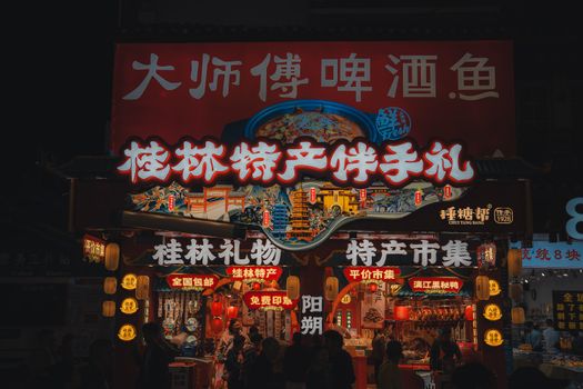 Vibrant scene at a night market in Guilin showcasing illuminated signs and local products.