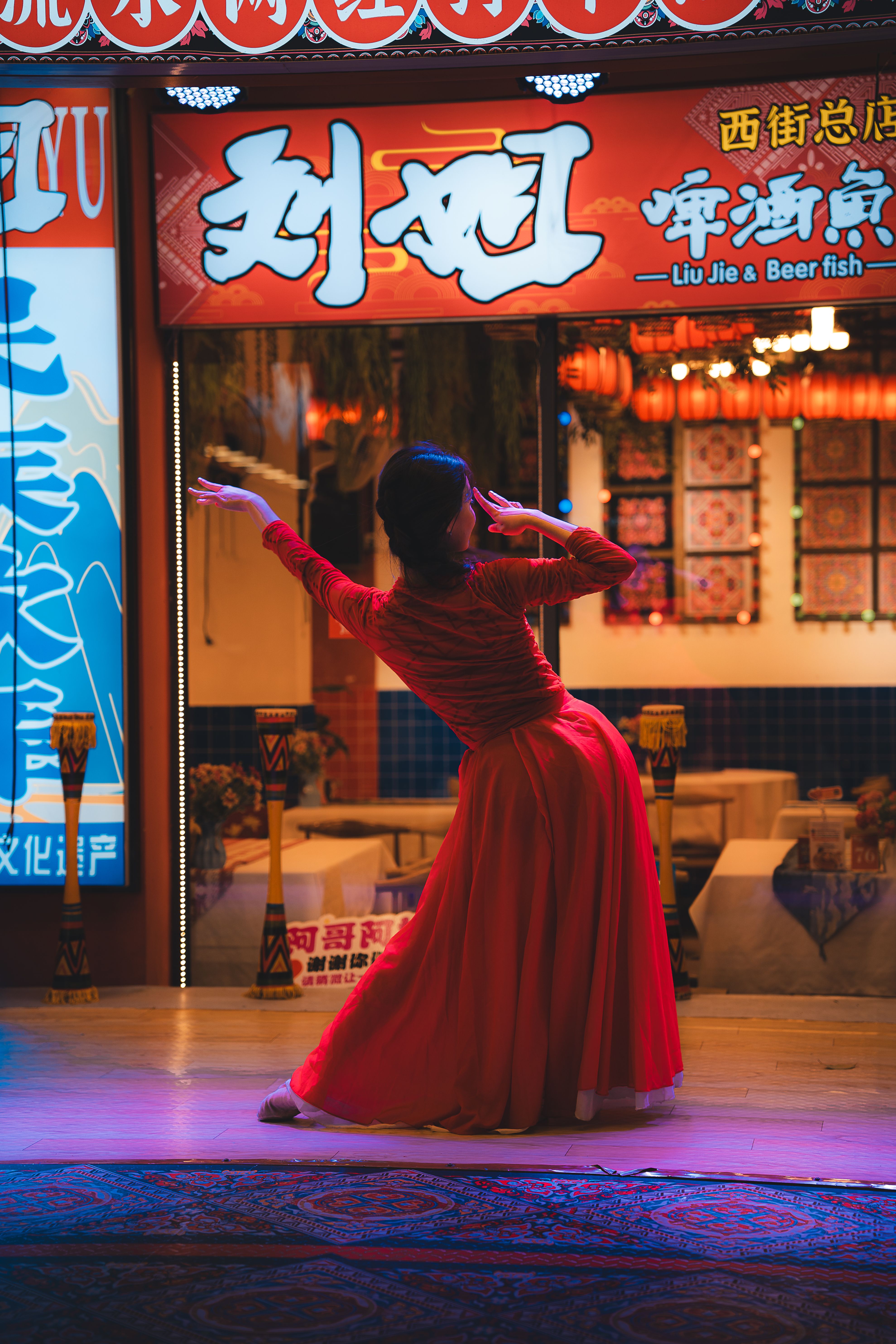 A dancer in a red dress performs gracefully in front of a restaurant in Guilin, China.