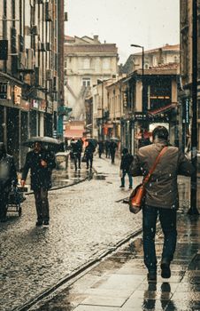 Busy city street with people walking in the rain, evoking a moody, cinematic vibe.