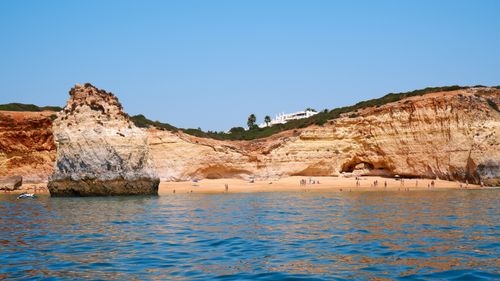 Free Beautiful Algarve beach with rugged cliffs and clear blue waters in Faro, Portugal. Stock Photo