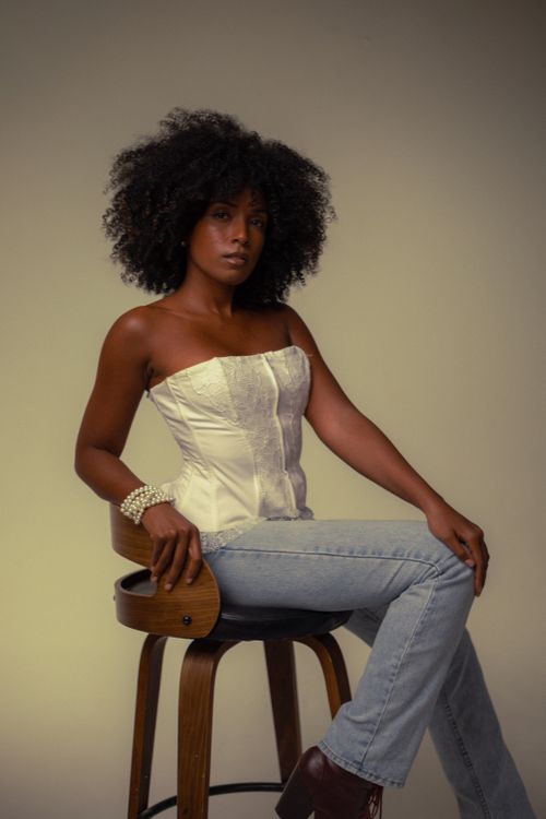 Free Elegant portrait of a woman seated in a studio wearing a white corset. Stock Photo