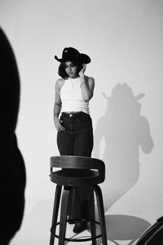 Artistic black and white portrait of a woman in a cowboy hat during a studio photoshoot.