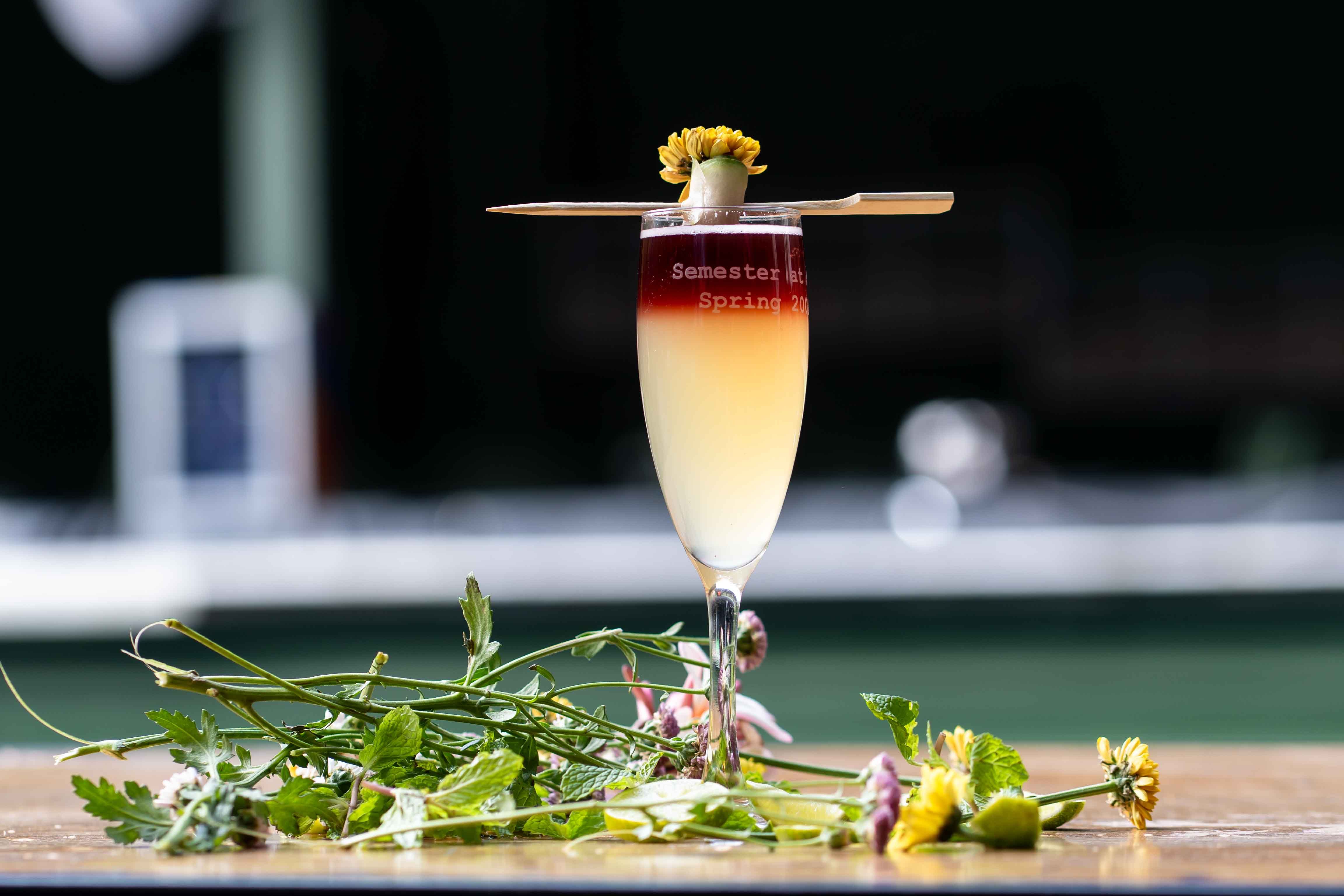 Sophisticated cocktail in a flute glass with floral garnish on a bright day.