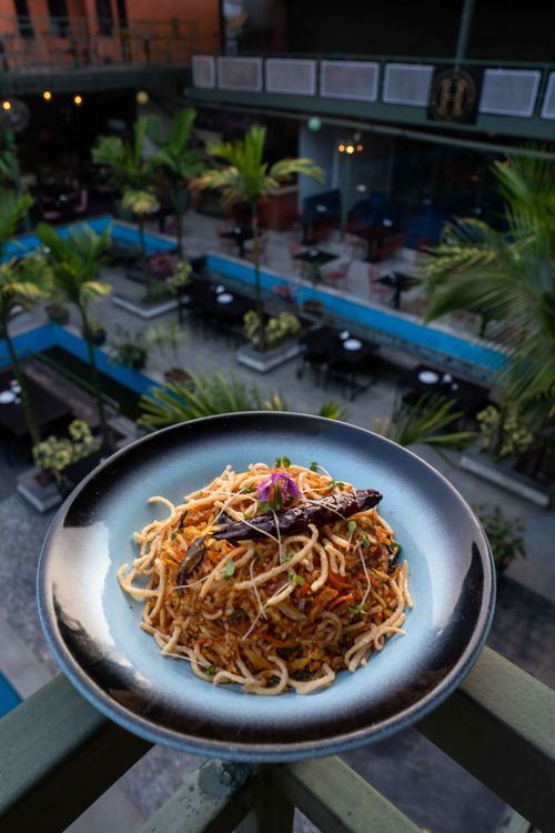 Free Delicious spicy noodles served in a vibrant outdoor dining restaurant, captured from an elevated angle. Stock Photo