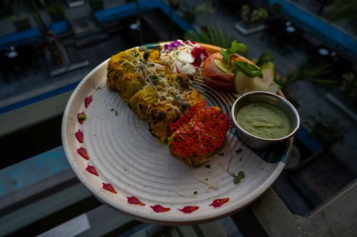 Free Appetizing Indian grilled tikka platter with chutney and fresh garnishes on a stylish plate. Stock Photo