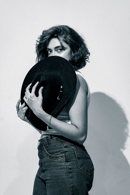 Free Artistic black and white portrait of a woman holding a hat, in a classic and moody style. Stock Photo
