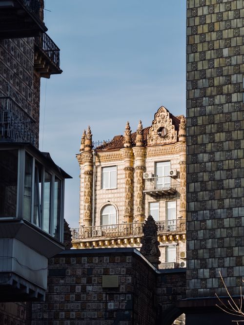 Free Vintage building with ornate architecture framed by modern structures in an urban setting, viewed during the day. Stock Photo