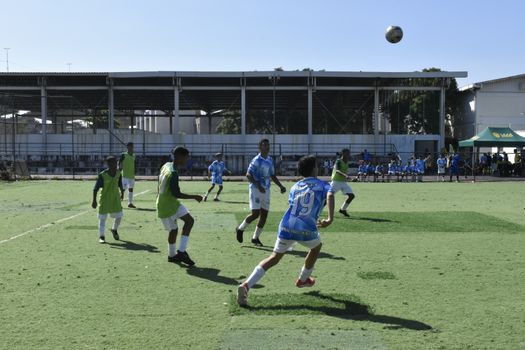 Youth soccer players engaged in a competitive match outdoors under clear skies.