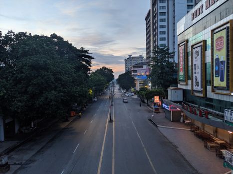 Serene city street in Yangon, Myanmar at dawn with empty roads and buildings.