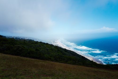 Free Breathtaking view of a lush coastal landscape with ocean waves meeting the horizon. Stock Photo