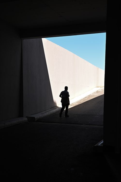 Free Silhouetted person walking through a dramatic urban tunnel entrance in daylight. Stock Photo