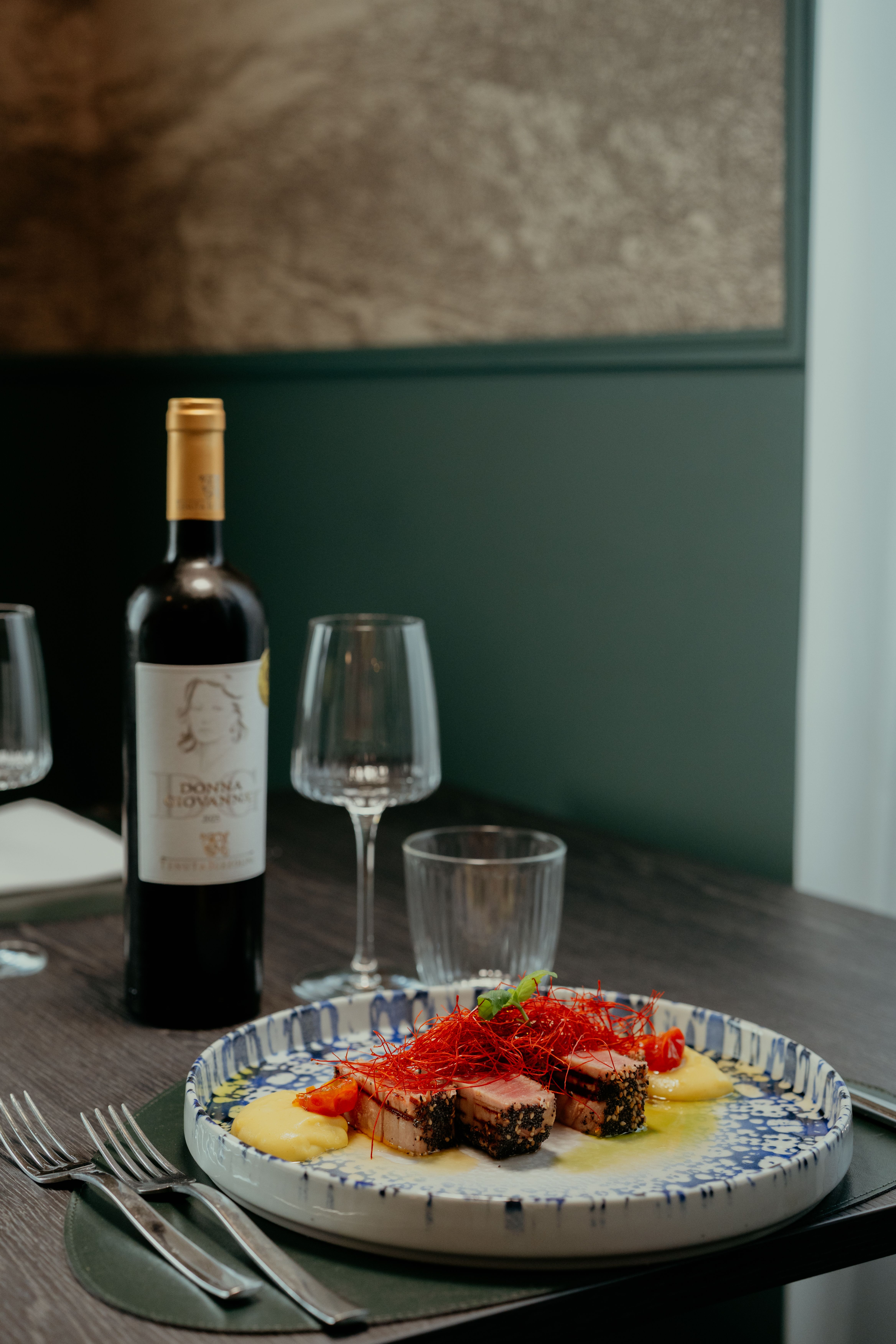 Elegant gourmet dish with red wine in a cozy Calabria restaurant setting.
