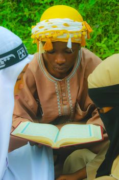Young adults reading a book together outdoors in Abuja, Nigeria.