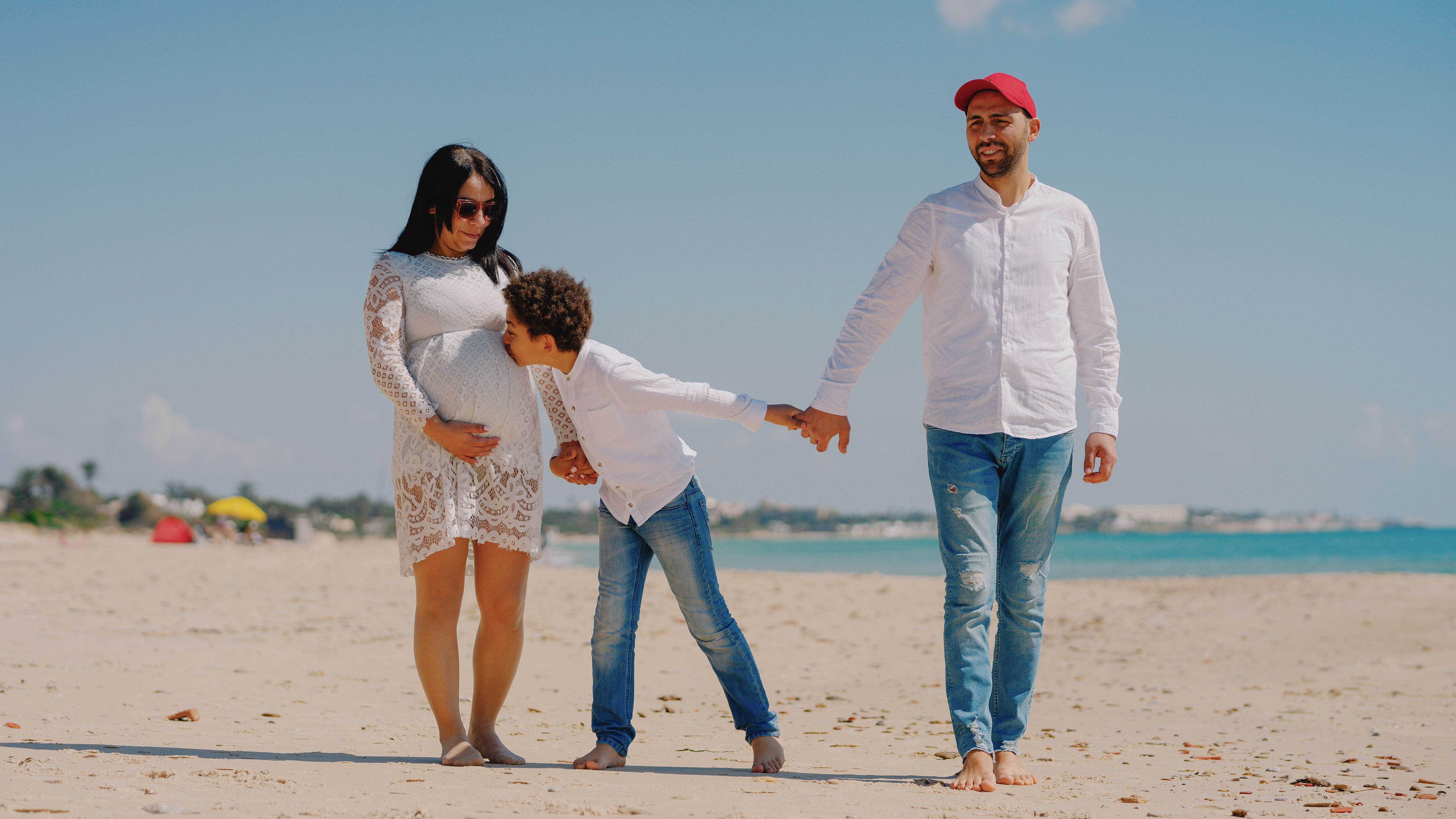 Pregnant woman walking with husband and child on a beach in Tunisia