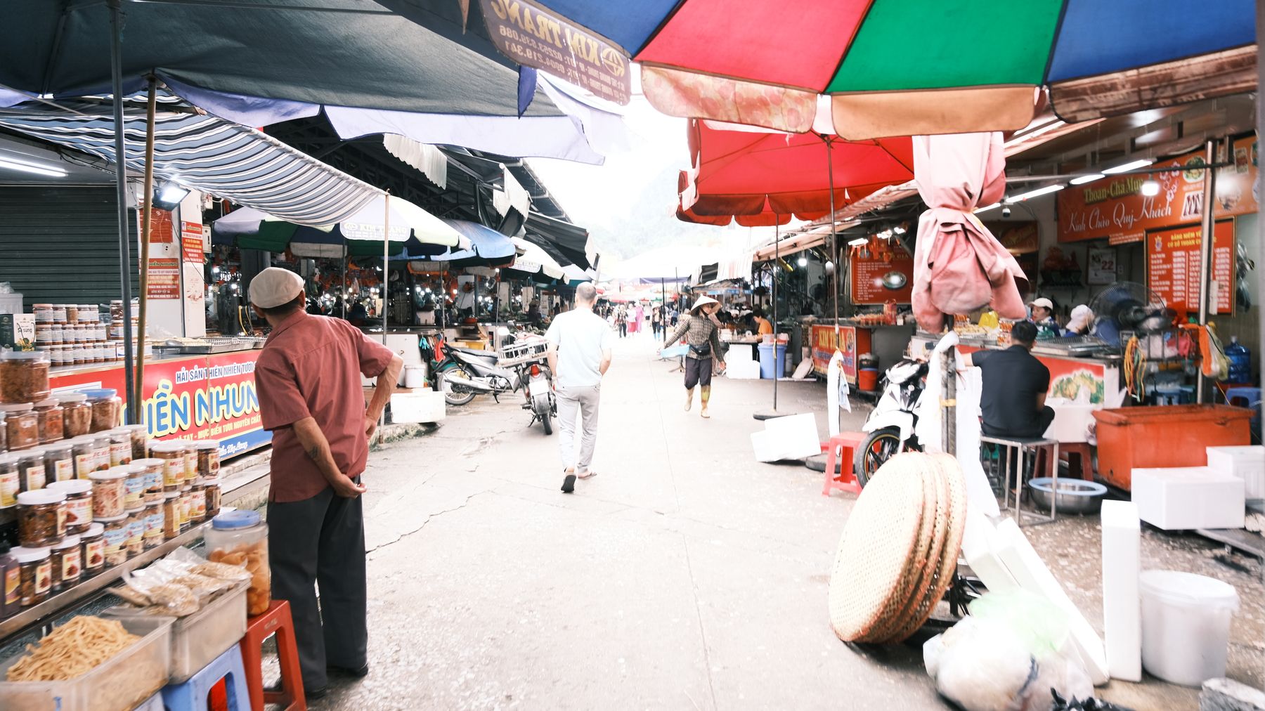 Bustling street market with colorful umbrellas and diverse foods, capturing a lively day scene.