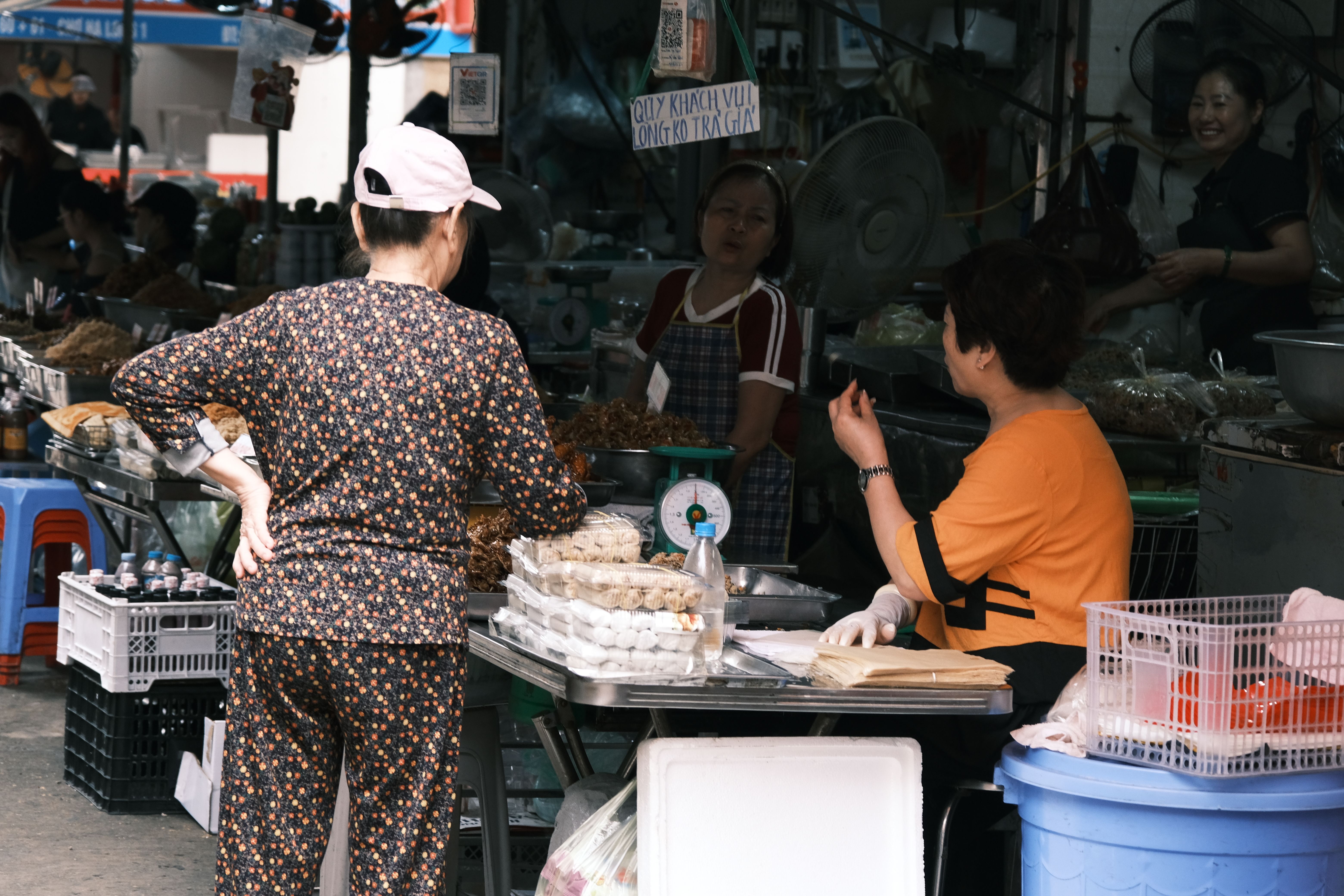 A lively street market with vendors and shoppers engaging in transactions over fresh produce.