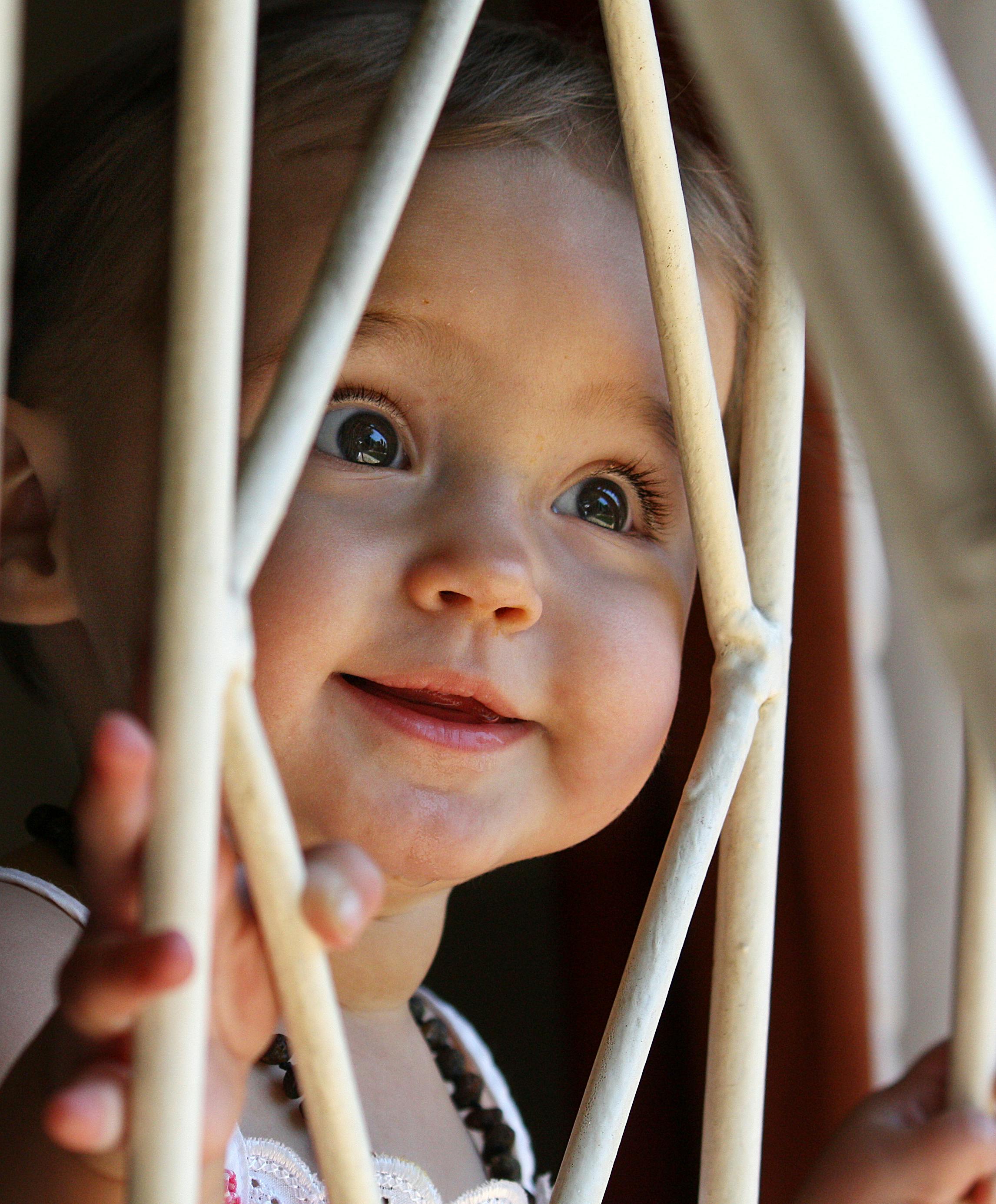 smiling baby holding white metal frame