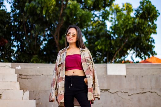 Stylish young woman poses confidently in casual urban fashion setting.
