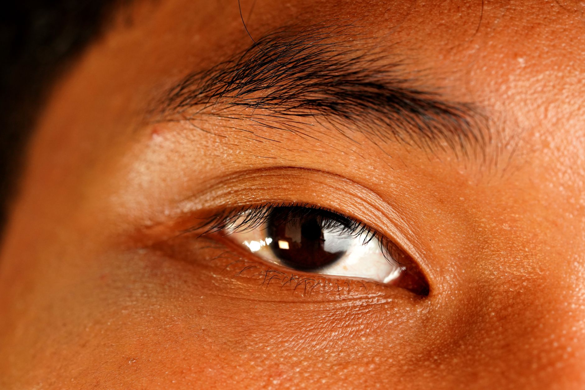 A detailed macro close-up of a human eye showing the eyelid, lashes, and the level set of the outer corner