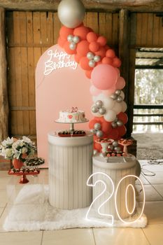 Beautiful 20th birthday party decorations with balloons, cake, and a neon sign.