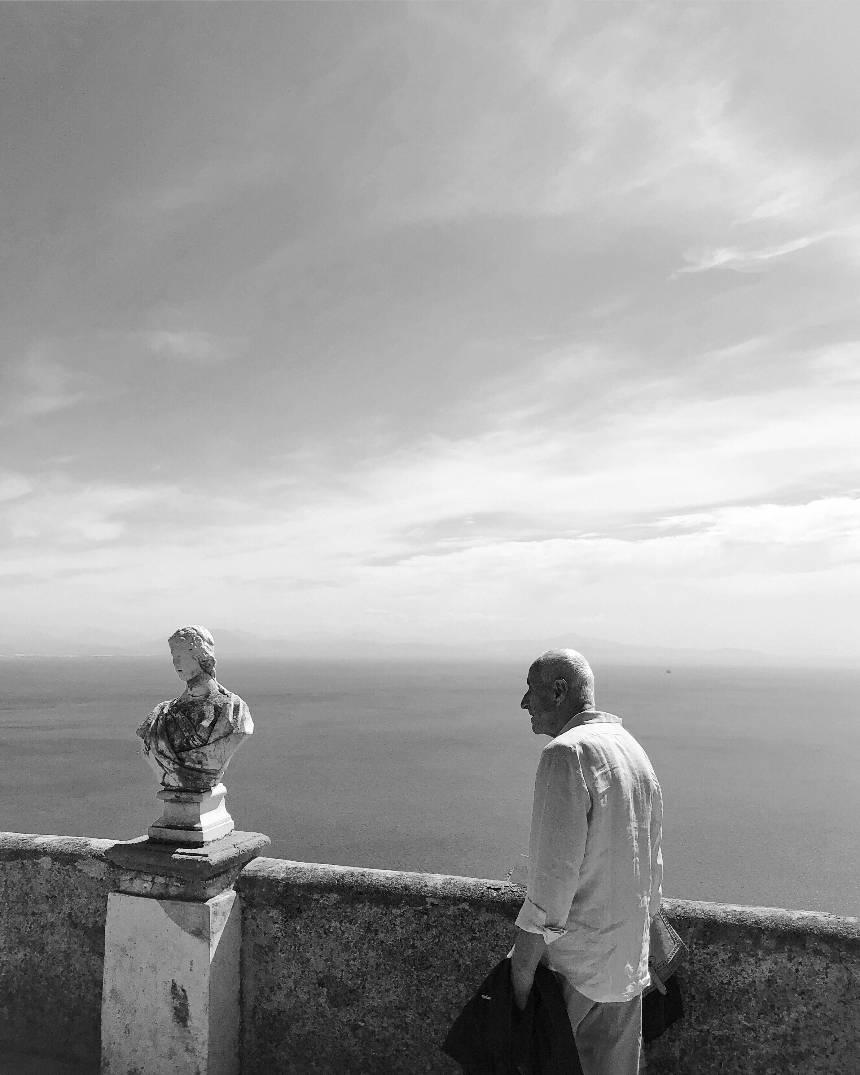 An elderly man gazes at the horizon from a scenic viewpoint in Ravello, Italy.