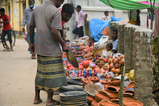 Local vendors selling pottery and crafts in a vibrant street market in Rangpur, Bangladesh.