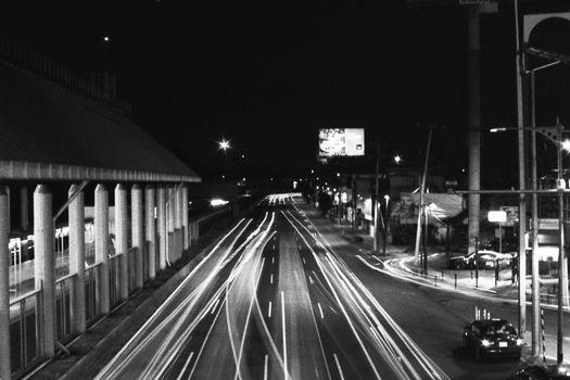 Long exposure showing city street traffic lights at night in black and white.