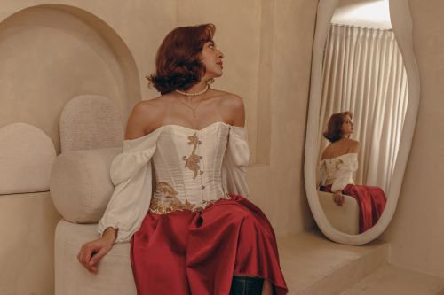 Free A woman in vintage attire sits elegantly next to a mirror, creating a classic reflection. Stock Photo