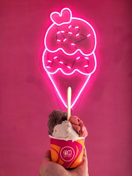 粉色霓虹冰淇淋标志前，色彩缤纷的冰淇淋杯映衬着充满活力的墙壁