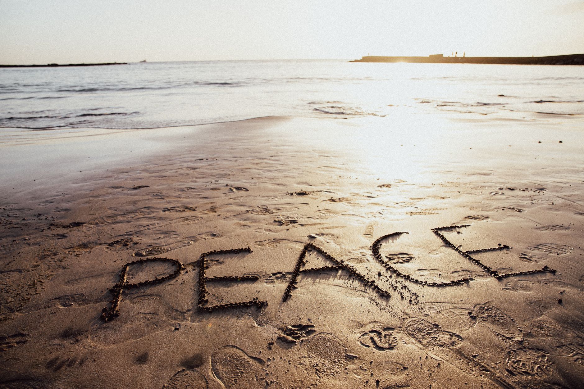 Peace written on a tranquil beach at sunset in the Canary Islands symbolizing tranquility and unity.