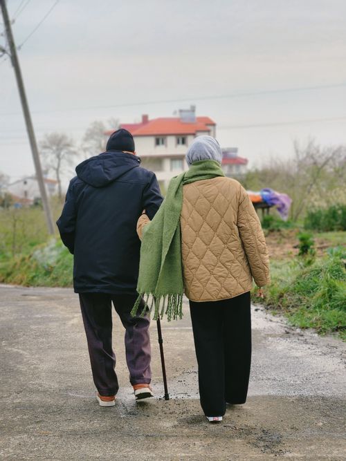 Free Elderly couple walks arm-in-arm on a countryside path, showcasing companionship and nature. Stock Photo
