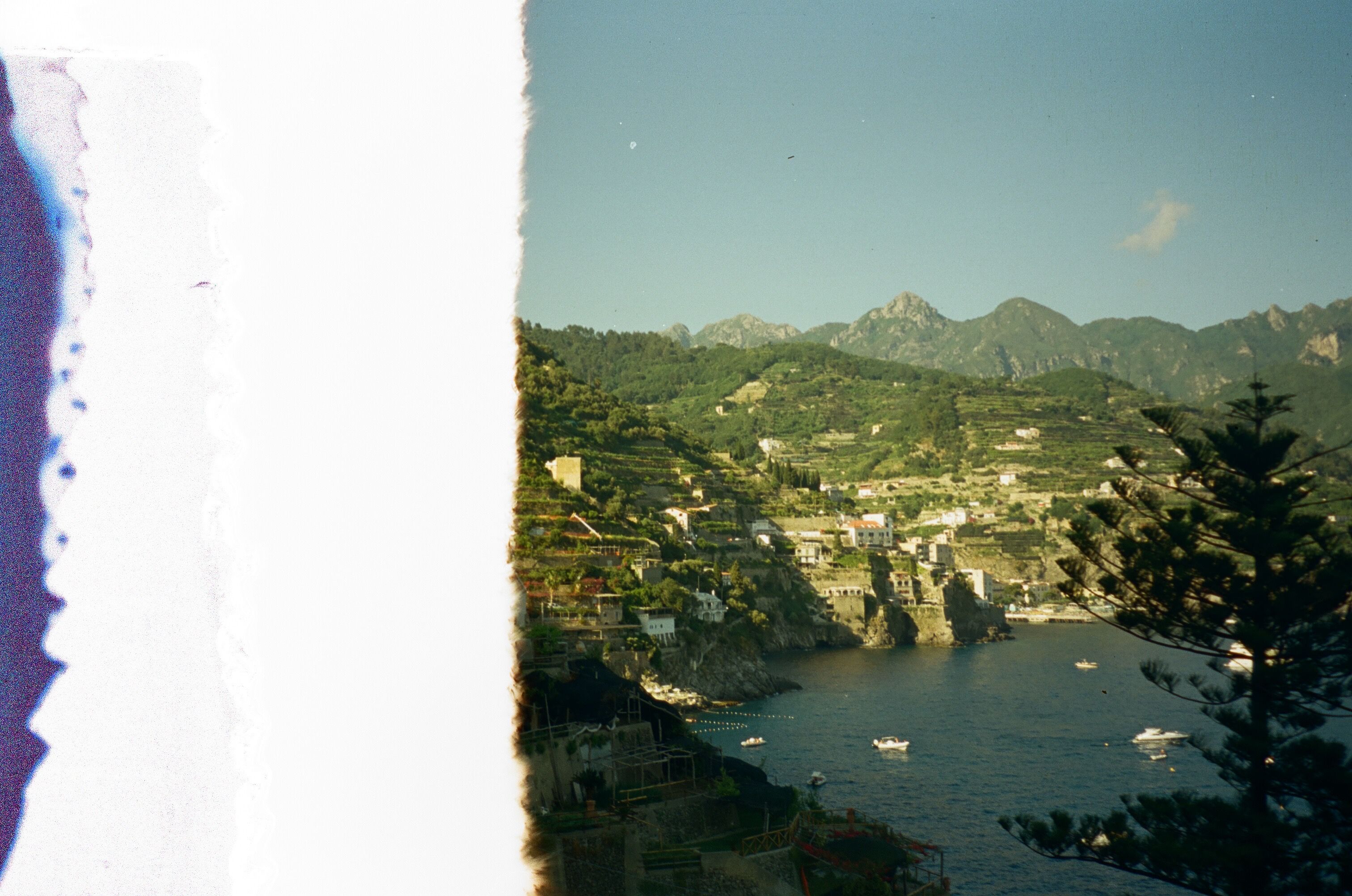 A picturesque view of the Italian Riviera with mountains, coastline, and boats.
